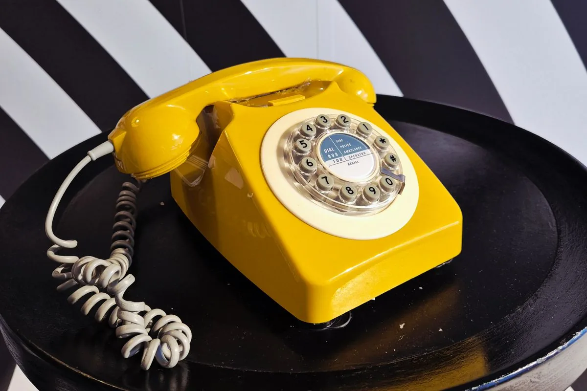 Żółty telefon tarczowy na czarnym stole